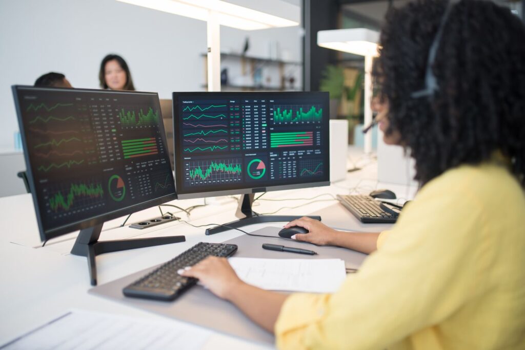 inline financial services analyst 8204355 A financial analyst reviewing fund performance dashboards on dual monitors