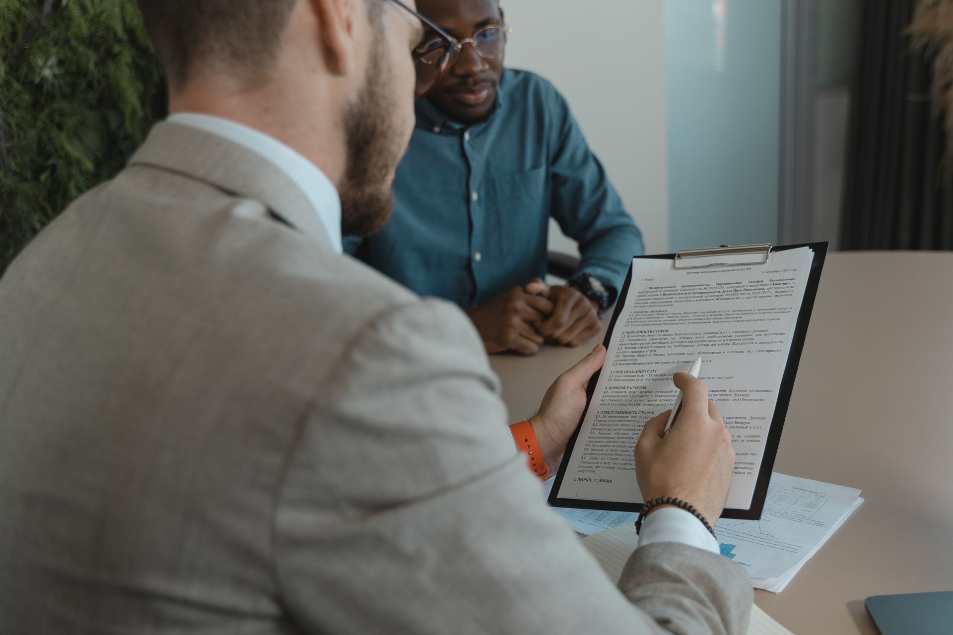 Hiring manager reviewing a contract on a clipboard with a candidate across the desk