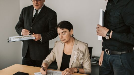 Three finance professionals reviewing printed financial documents together in an office