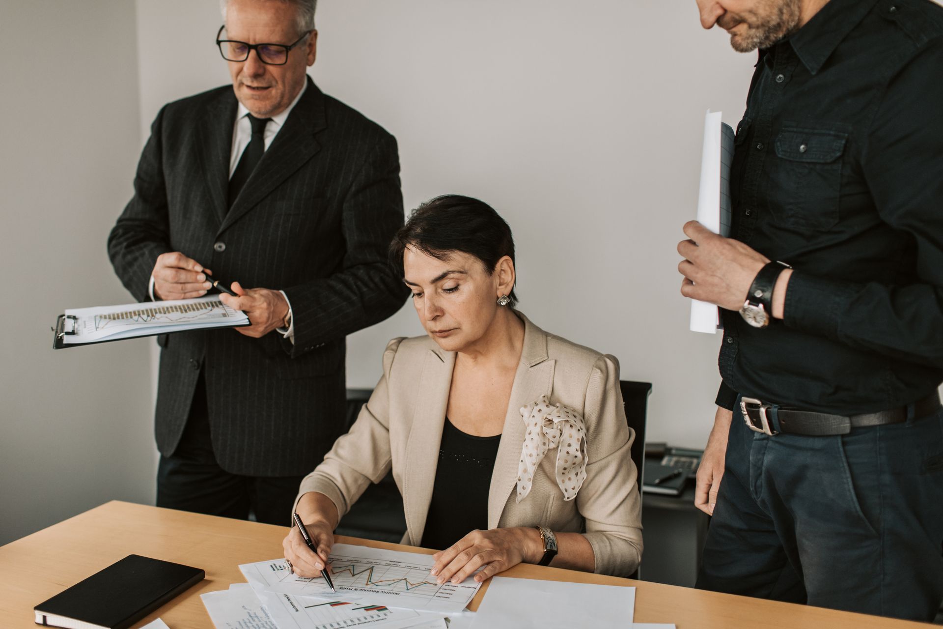 Three finance professionals reviewing printed financial documents together in an office
